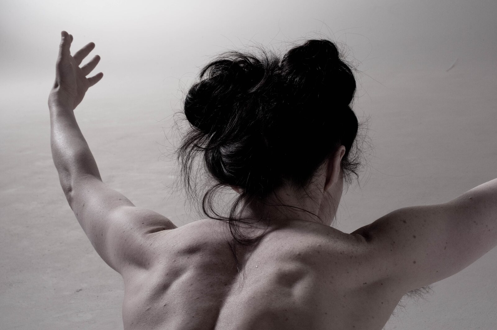 A woman seen from behind with arms lifted, showing a strong back